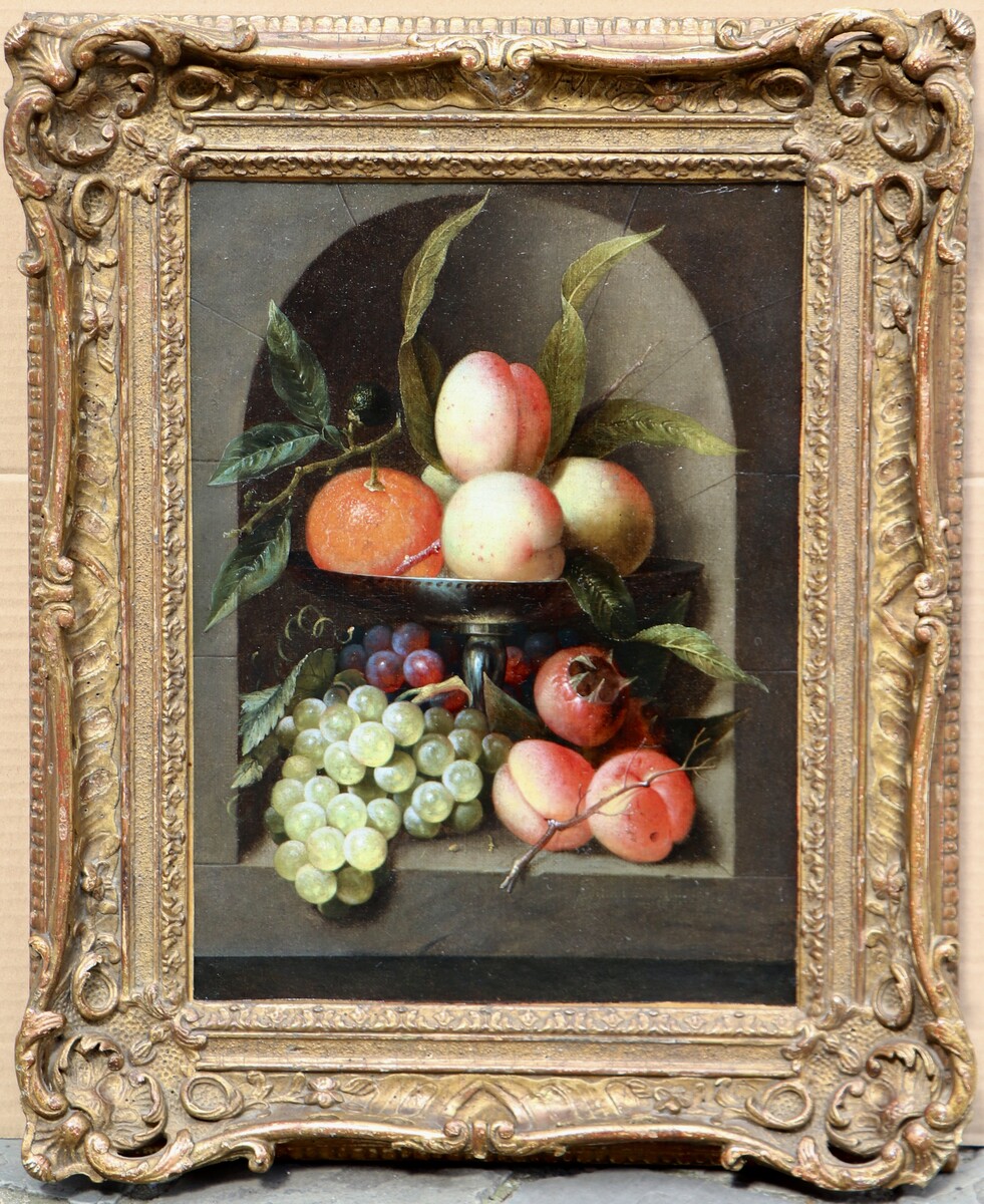 A fruit still life in a silver tazza standing in a stone niche