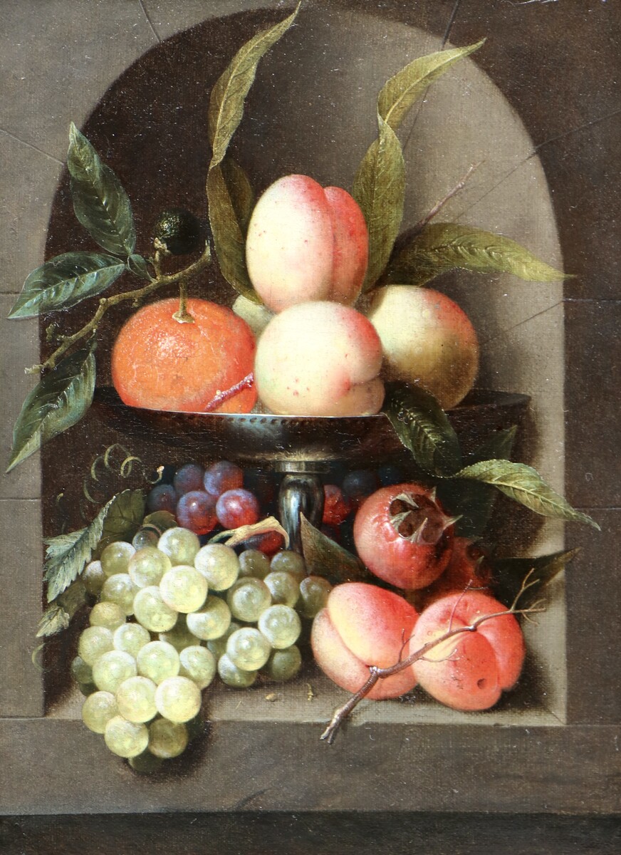 A fruit still life in a silver tazza standing in a stone niche