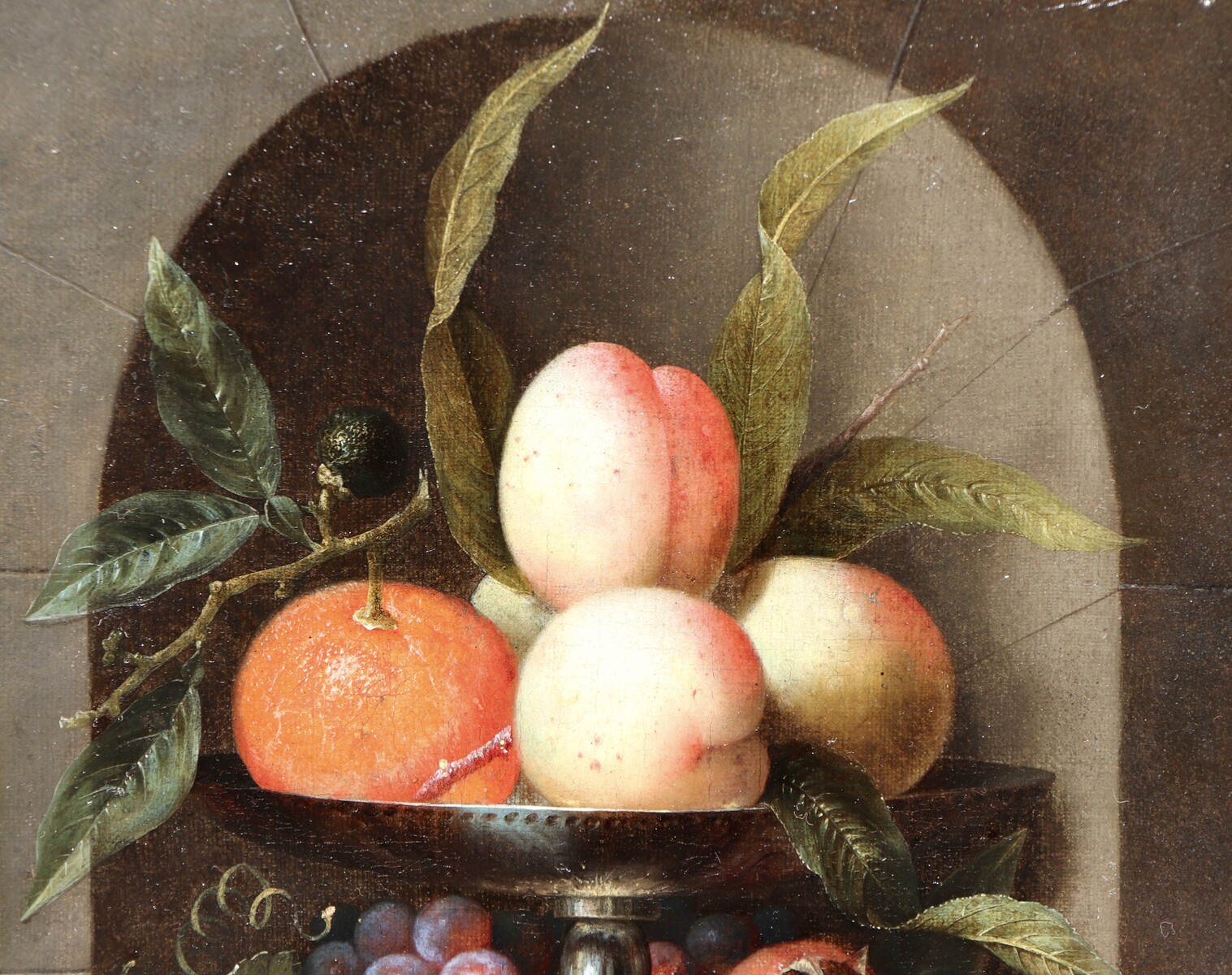 A fruit still life in a silver tazza standing in a stone niche