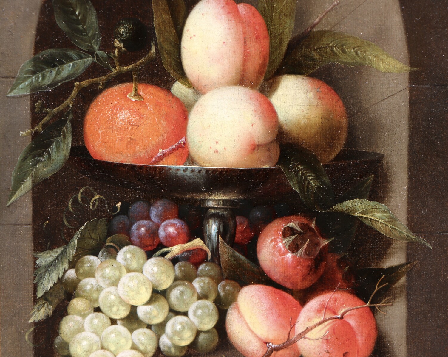 A fruit still life in a silver tazza standing in a stone niche