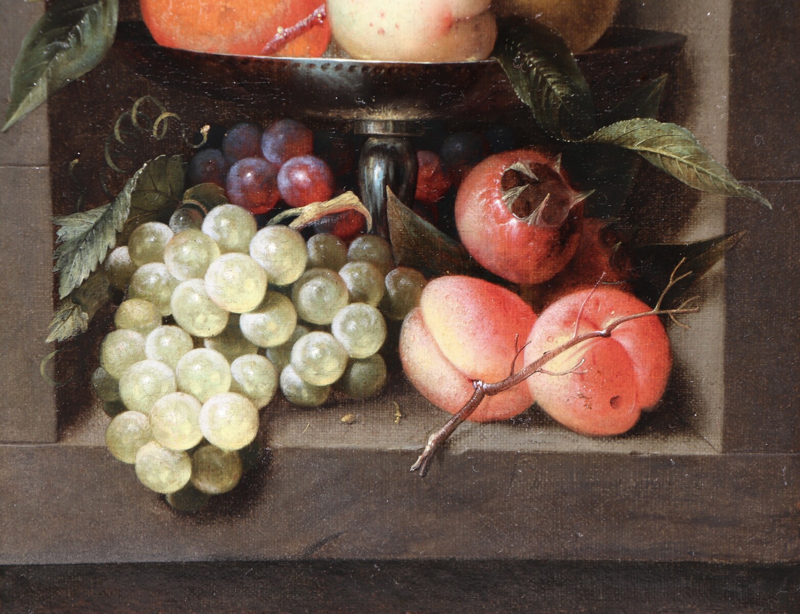 A fruit still life in a silver tazza standing in a stone niche