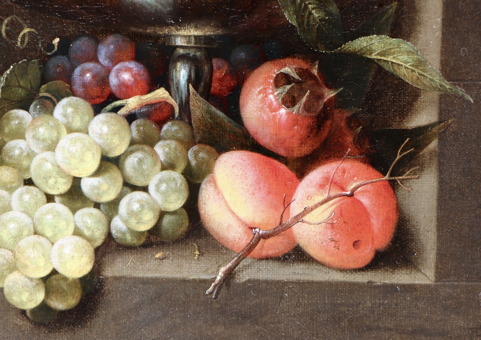 A fruit still life in a silver tazza standing in a stone niche