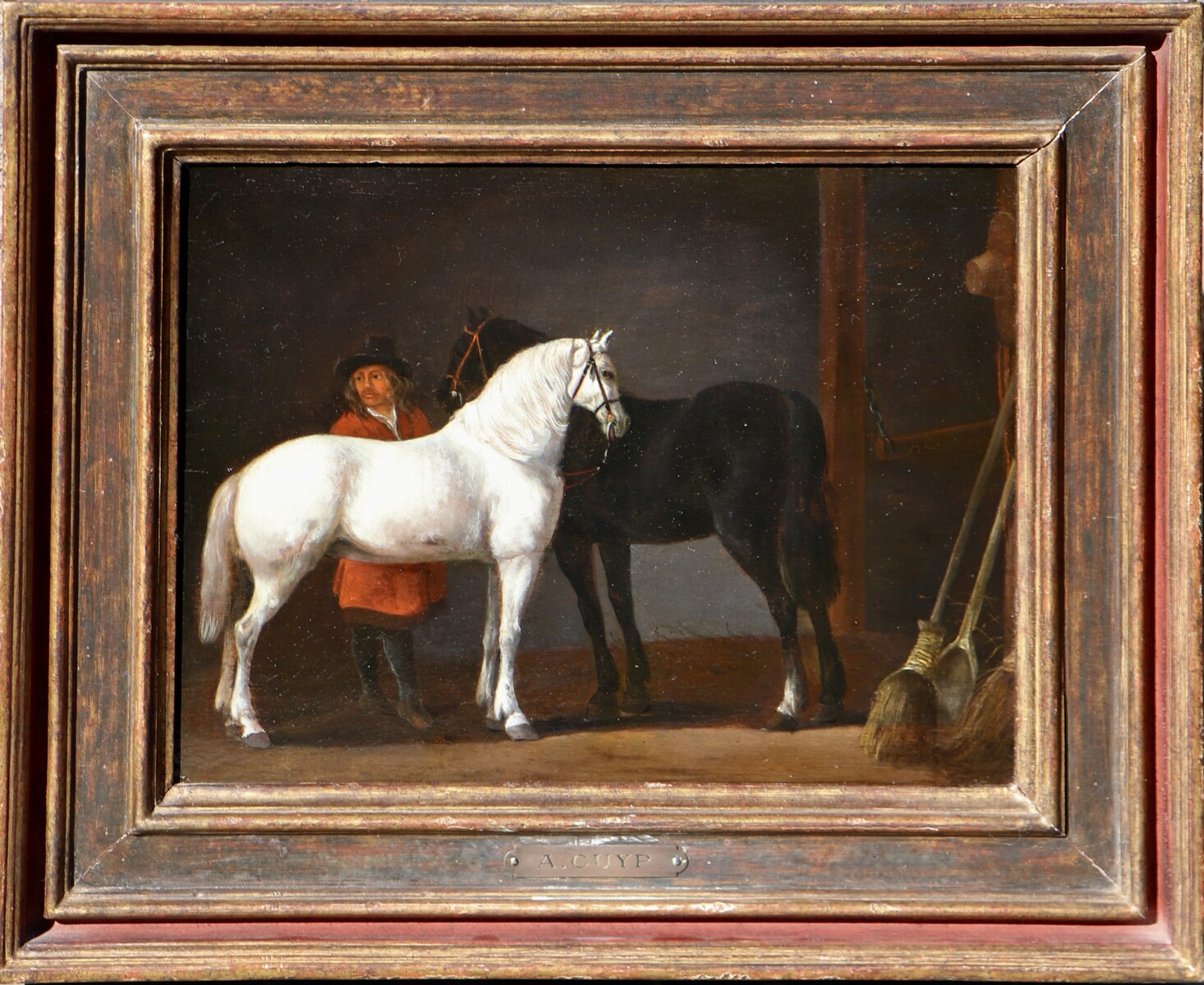 Two horses and a groom in a stable interior