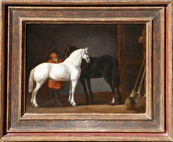 Two horses and a groom in a stable interior