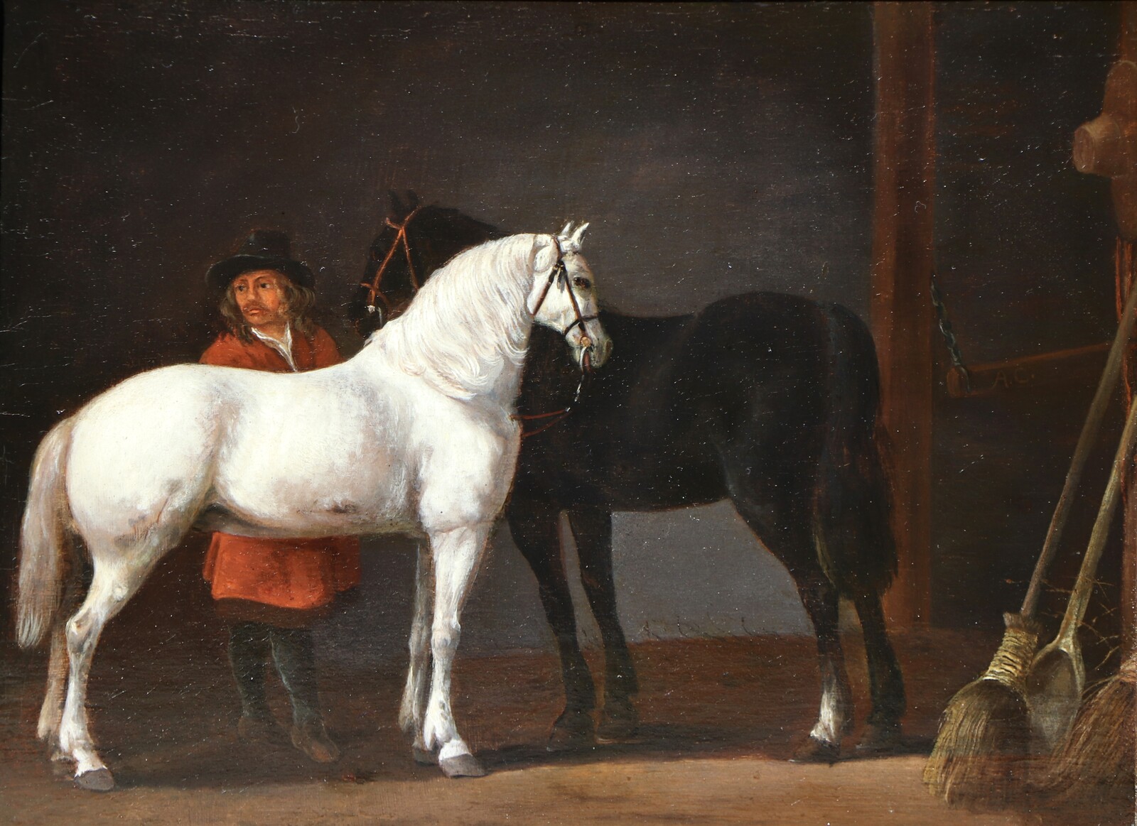 Two horses and a groom in a stable interior