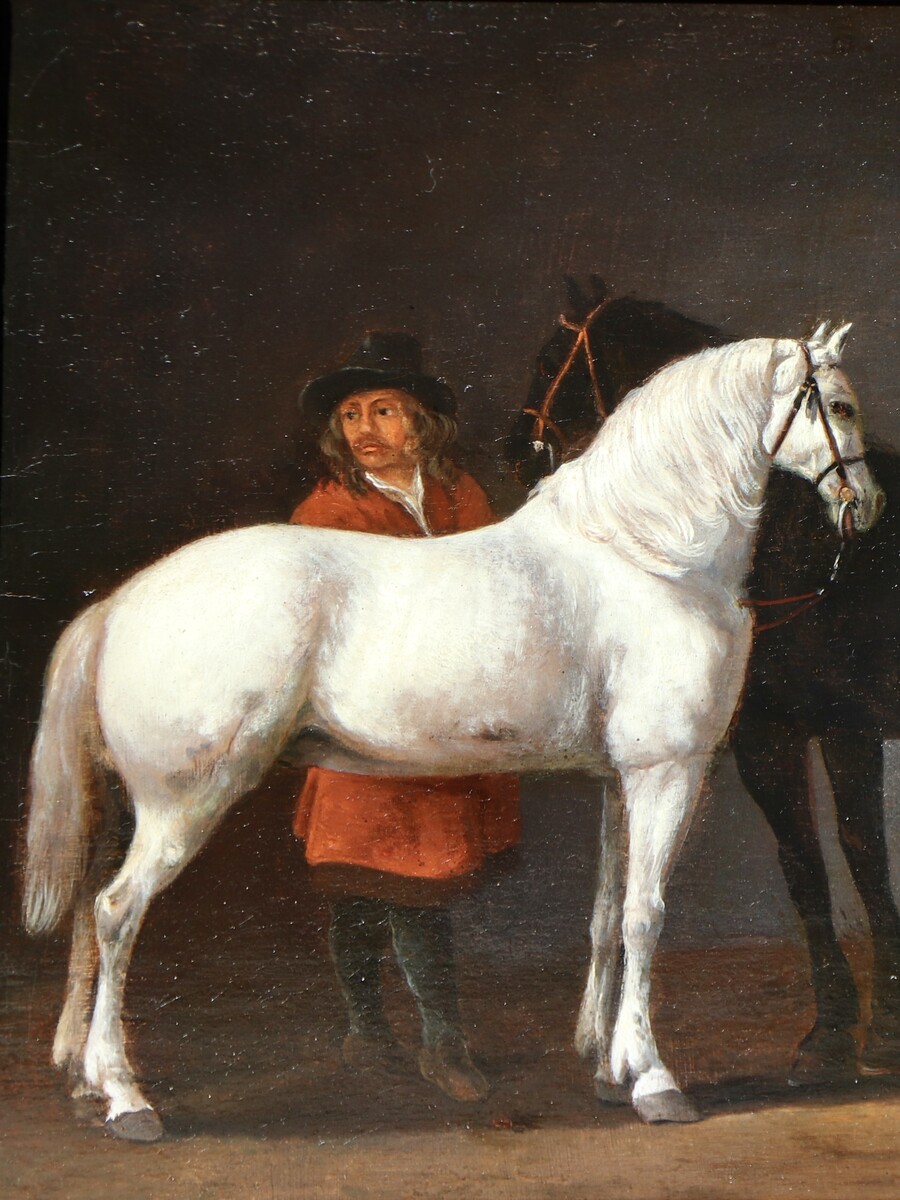 Two horses and a groom in a stable interior