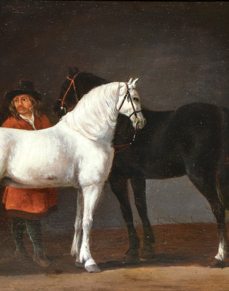 Two horses and a groom in a stable interior