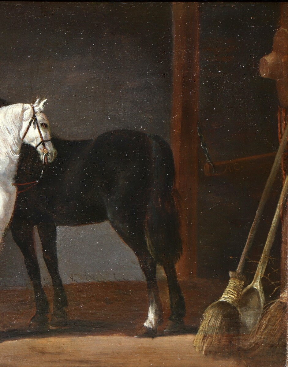 Two horses and a groom in a stable interior