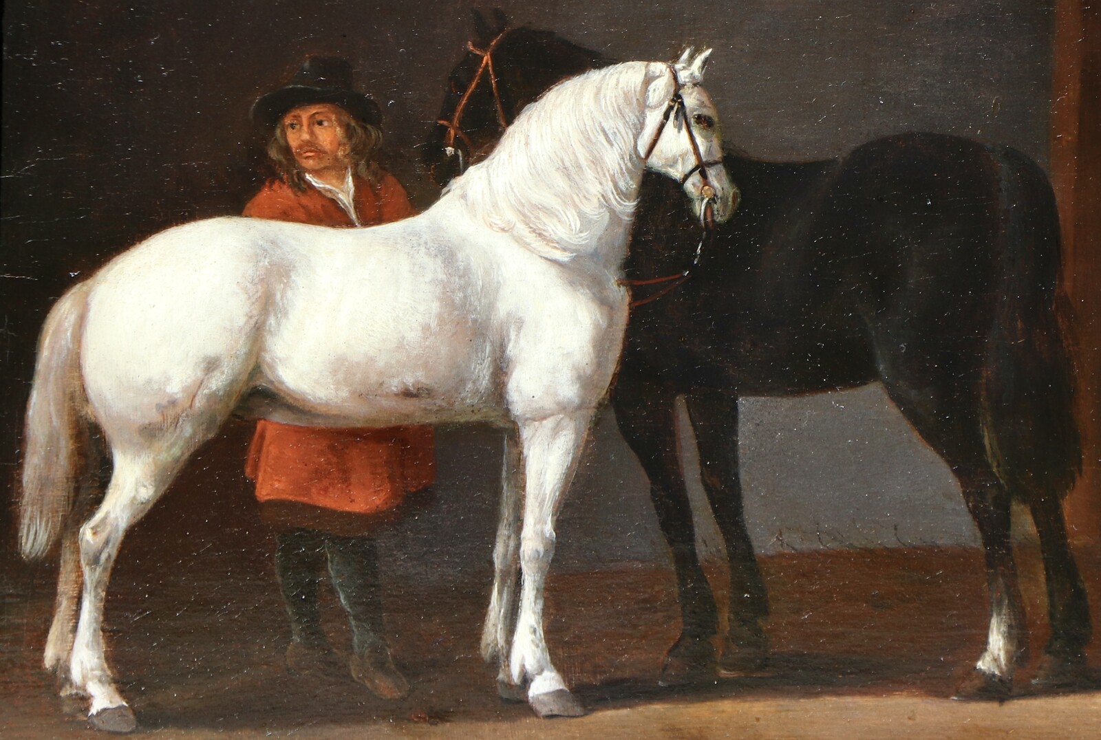 Two horses and a groom in a stable interior